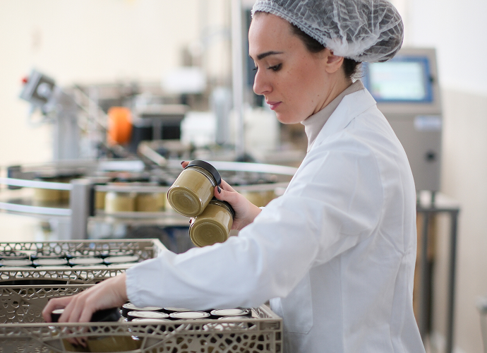foto di una operaia mentre sistema accuratamente i barattoli nei container